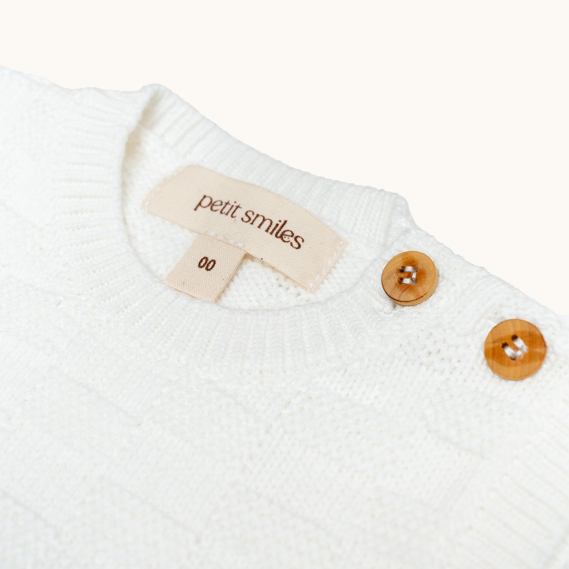 KNITTED BUTTONED WAISTCOAT - CREAM; 100% Organic Cotton; Waistcoat made from GOTS-certified organic cotton; Wooden button at shoulder for easy dressing; Rib finish at neck, hem and cuffs; Relaxed fit.
