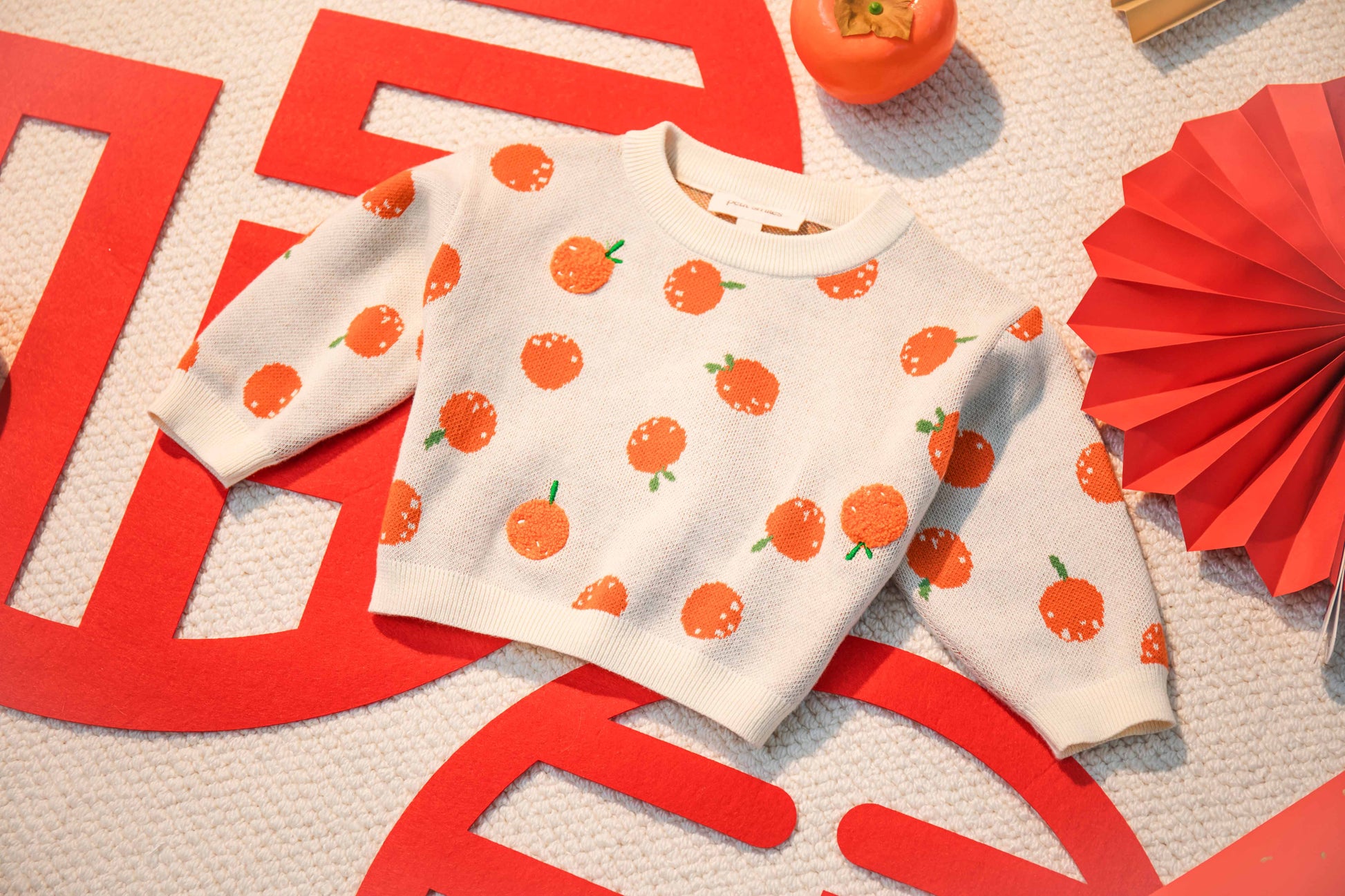 BABIES & KIDS KNITTED PULL OVER - CNY; 100% Organic Cotton; Jacquard Pull Over made from GOTS-certified organic cotton; 'Tangerine' Jacquard pattern with some towel embroidery artwork techniques; Rib finish at neck, cuffs and hem; Dropped shoulder; Relaxed fit; The younger model wears size 0; older model wears size 4.